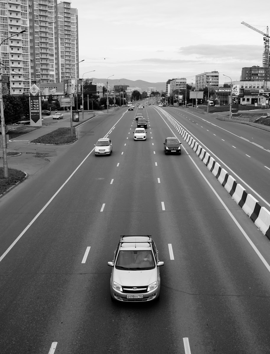 Black and white photo of cars driving in an urban area – Highlighting the importance of understanding car insurance coverage.